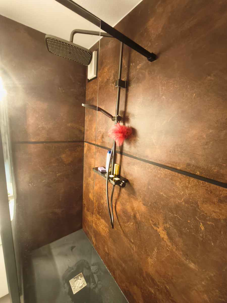 Douche WasserKraft noire installée sur panneaux muraux effet cuivre